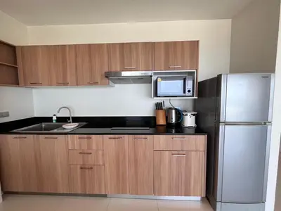 a kitchen with wooden cabinets and a stainless steel refrigerator at Sunset Plaza Karon Seaview in Karon Beach