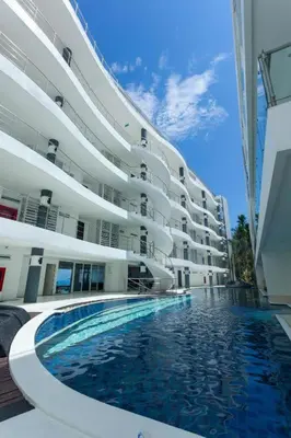 a large building with a swimming pool in front of it at Sunset Plaza Karon Seaview in Karon Beach