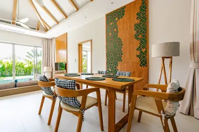 a dining room with a wooden table and chairs at Tropical Family Pool Villa - Bang Tao in Laguna Phuket