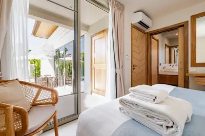 a bedroom with a bed and a chair and a balcony at Tropical Family Pool Villa - Bang Tao in Laguna Phuket