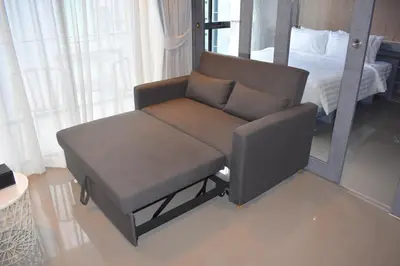 a reclining chair in a room with a bed at Oasis in CityGate 1BR Suite in Kamala Beach