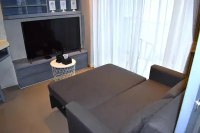 a living room with a couch and a flat screen tv at Oasis in CityGate 1BR Suite in Kamala Beach