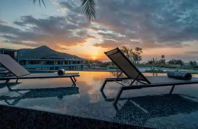 two lounge chairs sitting on top of a swimming pool at Oasis in CityGate 1BR Suite in Kamala Beach
