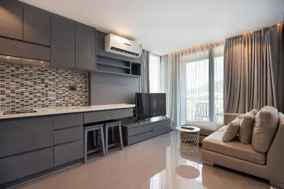 a living room with a tv and a couch and a kitchen at Tropical Kamala Pool View 1 BR CTG B206 in Kamala Beach