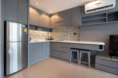 a kitchen with gray cabinets and a stainless steel refrigerator at Tropical Kamala Pool View 1 BR CTG B206 in Kamala Beach