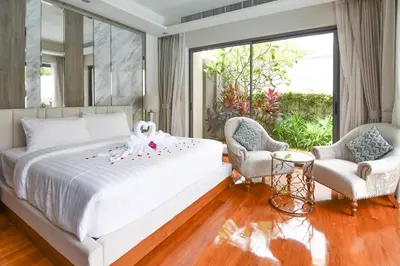 a bedroom with a large white bed and two chairs at Breeze Villa - Luxury Relaxation in Phuket in Ban Thalat Choeng Thale
