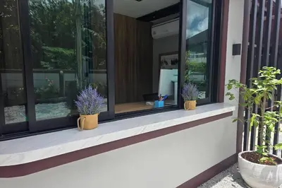 a house with two plants in pots on a window at Resort Thalang in Phuket