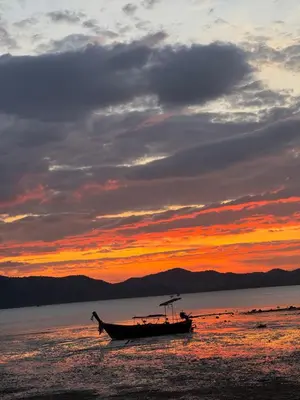 a boat sitting on the beach at sunset at Baan Rattana in Ko Yao Noi