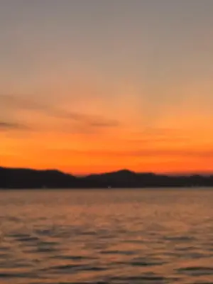 a sunset over the water with mountains in the background at Baan Rattana in Ko Yao Noi