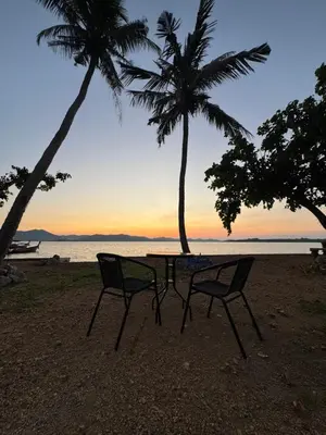 a table and chairs on a beach with palm trees at Baan Rattana in Ko Yao Noi