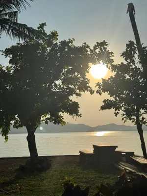 a sunset over the water with trees and benches at Baan Rattana in Ko Yao Noi