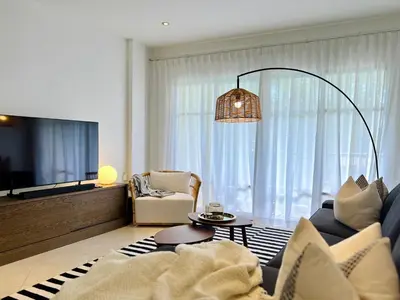 a living room with a couch and a tv at Baan Puri Serviced Apartment by RESAVA in Surin Beach