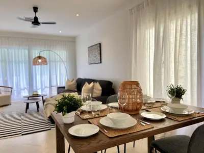 a living room with a table with plates and wine glasses at Baan Puri Serviced Apartment by RESAVA in Surin Beach
