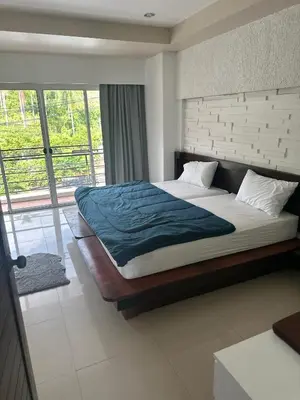 a bedroom with a large bed and a large window at Bestin Kata in Karon Beach