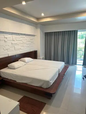a bedroom with a large bed and a large window at Bestin Kata in Karon Beach