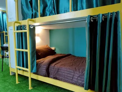 a bedroom with a bunk bed with blue curtains at Banana Bunkhouse Hostel in Rawai Beach