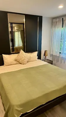 a bedroom with a large bed with a green blanket at 1 br Cozy Orchid at The Title Nai Yang in Nai Yang Beach