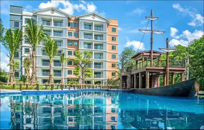 a hotel with a large swimming pool in front of a building at 1 br Cozy Orchid at The Title Nai Yang in Nai Yang Beach