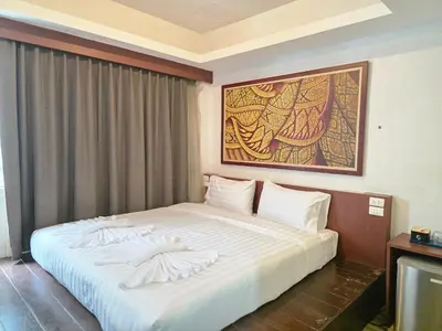 a bedroom with a large white bed with a painting on the wall at Le Moon in Patong Beach