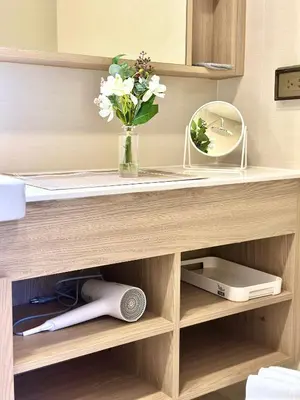 a wooden shelf with a vase of flowers and a mirror at Skypark Laguna 2 Bedroom Apartment in Laguna Phuket