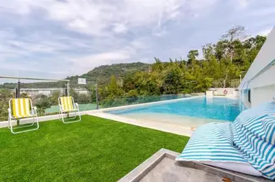a swimming pool with two chairs and a bed at Чудесная видовая квартира Fantasea пляж Камала in Kamala Beach