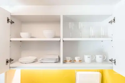 a kitchen with white cabinets with dishes and cups at Cassia Phuket, part of Banyan Group in Bang Tao Beach