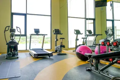 a gym with treadmills and exercise equipment and windows at Cassia Phuket, part of Banyan Group in Bang Tao Beach