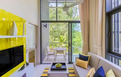 a living room with a couch and a tv at Cassia Phuket, part of Banyan Group in Bang Tao Beach
