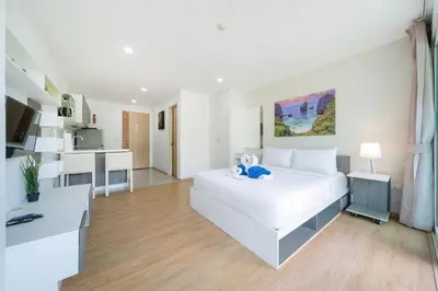 a white bedroom with a white bed and a kitchen at Mountain view apartment near Kata beach in Kata Beach