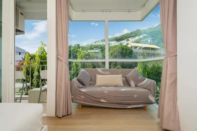 a living room with a couch in front of a large window at Mountain view apartment near Kata beach in Kata Beach