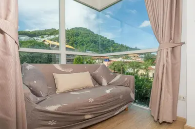 a couch in a room with a large window at Mountain view apartment near Kata beach in Kata Beach