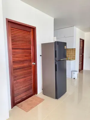 a kitchen with a refrigerator next to a wooden door at The President Park Condo Nanai, Patong, Phuket in Patong Beach