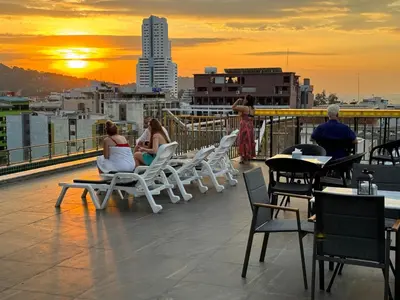 a group of people sitting on a roof watching the sunset at APK Hillview Hotel in Patong Beach