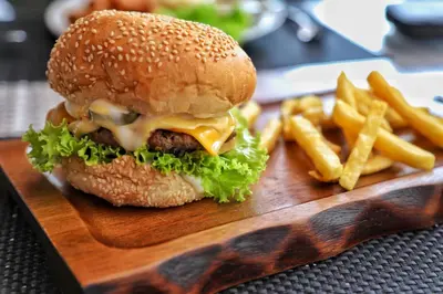 a hamburger and french fries on a wooden plate at APK Hillview Hotel in Patong Beach