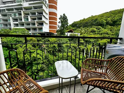 a balcony with two chairs and a white chair at Palmetto Park Condominium in Karon Beach