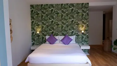 a bedroom with a large white bed with purple pillows at The Lush Apartments & Suites in Pilai Beach