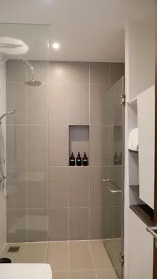 a bathroom with a shower stall with three bottles at The Lush Apartments & Suites in Pilai Beach