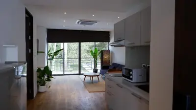 a kitchen with a microwave and a living room at The Lush Apartments & Suites in Pilai Beach