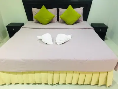 two towels on a bed with green and pink pillows at Srisuksan Klong Muang Beach in Klong Muang Beach