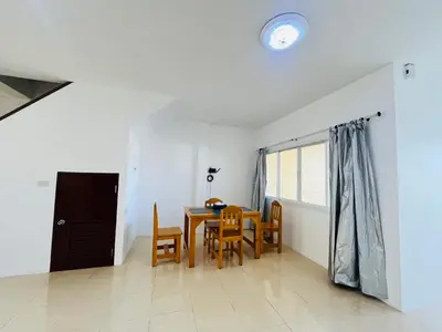 a dining room with a table and chairs and a clock at Winlee house in Ban Phlu Yai