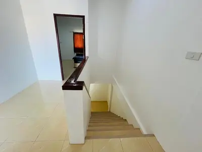 a stairway with a white wall and a stair case at Winlee house in Ban Phlu Yai