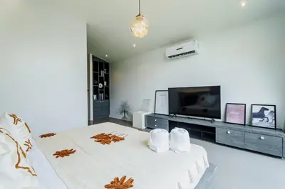 a white bedroom with a large bed and a flat screen tv at Harmony Exclusive Villa Bang Tao Phuket in Ban Thalat Choeng Thale