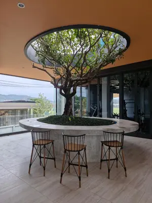 a table with two chairs and a tree in a building at Bellevue Lagoon Phuket 212 Bang tao operated by OK Group in Laguna Phuket