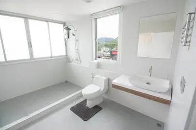 a white bathroom with a toilet and a sink at Spacious 2 Bedrooms 360deg Mountain-View Apartment in Ban Klang