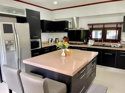 a kitchen with black cabinets and a white refrigerator at Kata Tropical Heights Villa - 4BR Private Pool in Kata Beach