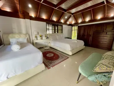 a bedroom with two beds and a chair in it at Kata Tropical Heights Villa - 4BR Private Pool in Kata Beach