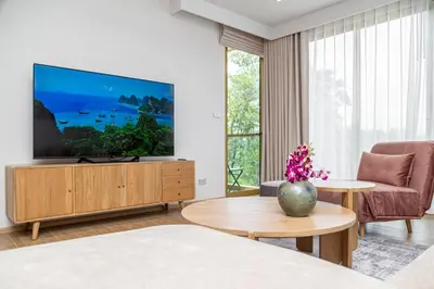 a living room with a flat screen tv on a wooden cabinet at Beachside 1 bedroom apartment 200 meters to Bang Tao Beach Manage by OCEAN HUB in Ban Thalat Choeng Thale