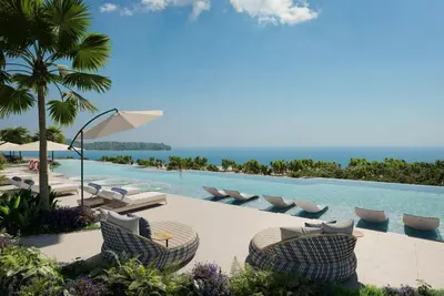 a pool at a resort with lounge chairs and the ocean at Beachside Lagoon Bang Tao Laguna by OK group in Ban Thalat Choeng Thale