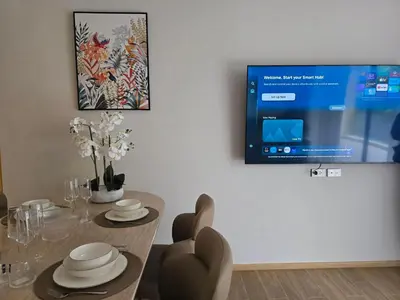 a dining room with a table and a tv on a wall at Beachside Lagoon Bang Tao Laguna by OK group in Ban Thalat Choeng Thale