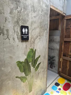 a sign on the side of a wall with a plant at THE REAL ESCAPE - Koh Yao Noi in Ko Yao Noi